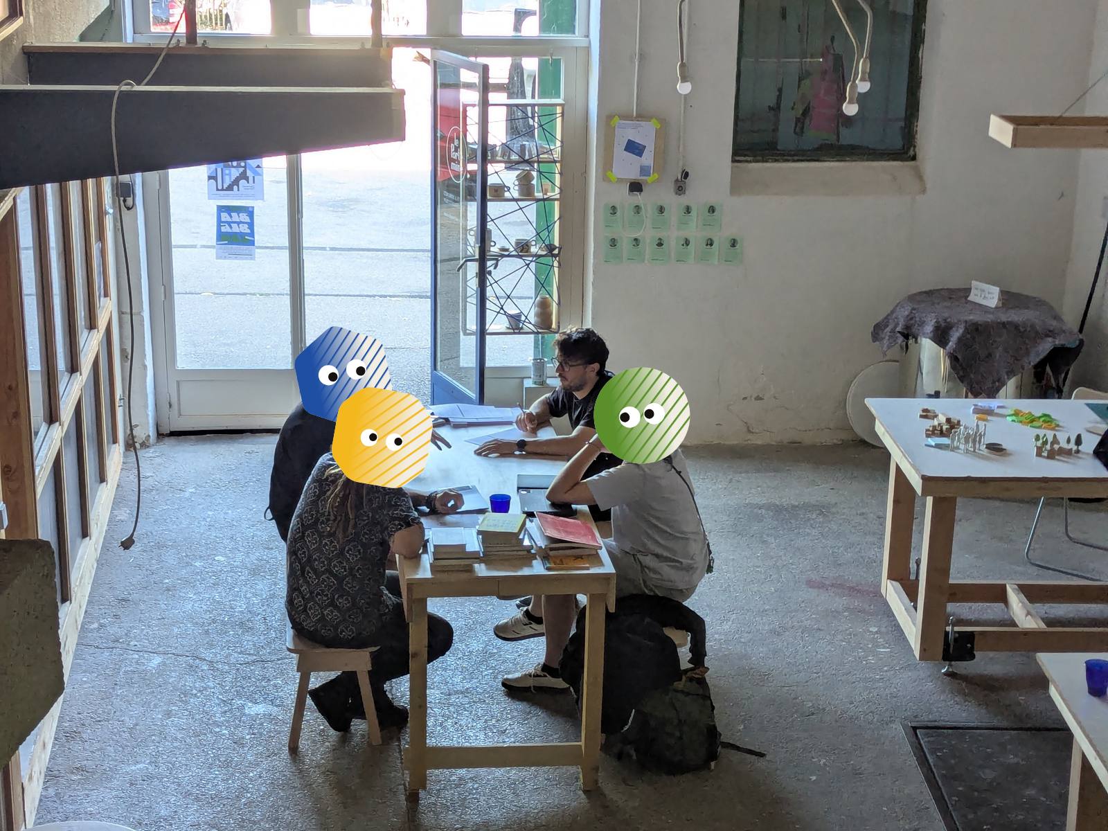 Jonathan Mazuel en échange avec trois participants autour de la table de travail du Portemine, vu depuis la mezzanine. Les visages des participants sont masqués par des personnages colorés.